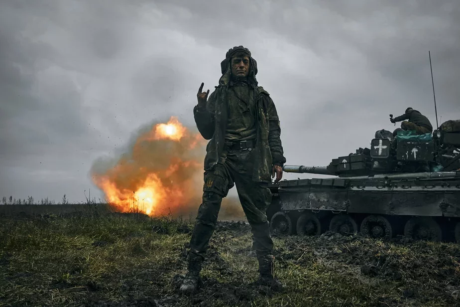 Ukrainski sałdat paziruje na fonie padbitaha rasijskaha tanka T-80. Fota: AP Photo/LIBKOS